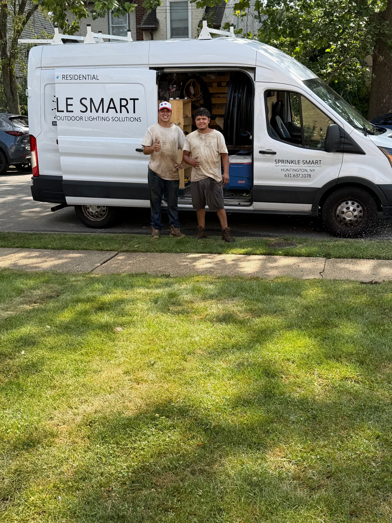 Two Sprinkle Smart team members standing beside their equipped service van