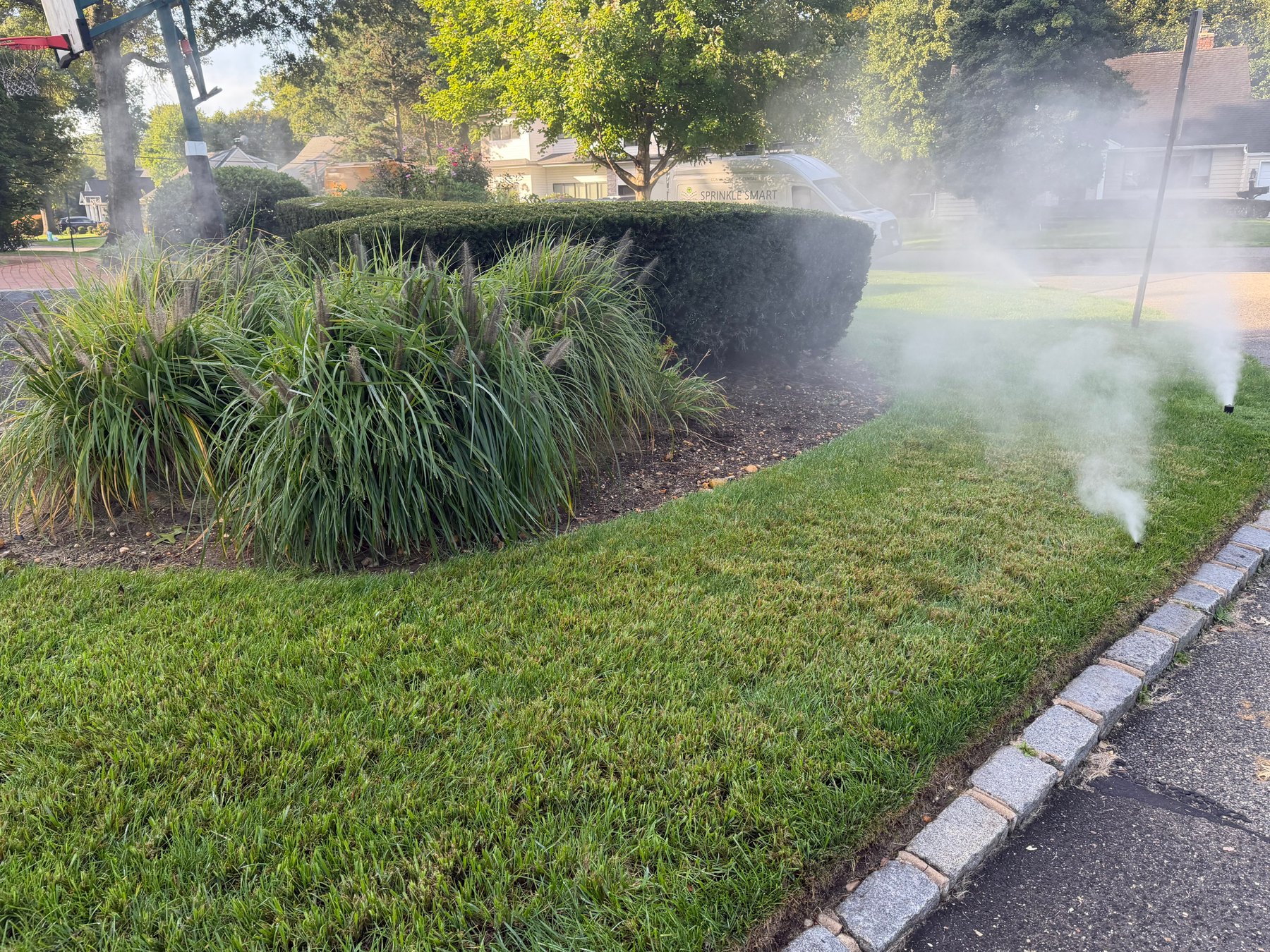 Sprinkler blowout on a lawn with the Sprinkle Smart service van in the background
